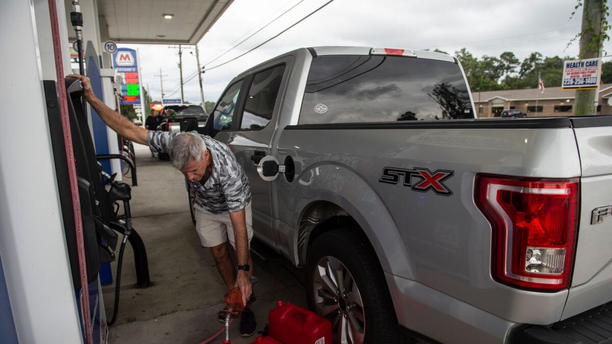 Gary Sullivan of Gulf Hills, fills extra gas containers at Marathon Gas in Ocean Springs, Miss., in preparation for Hurricane Ida. — AP