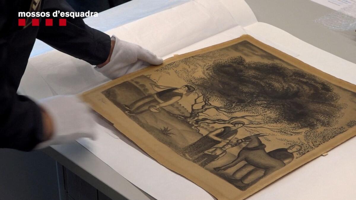 A Mosso d'Esquadra police officer handles a recovered charcoal drawing by Spanish artist Salvador Dali that had been stolen in Barcelona, Spain, in this handout photo released on Friday.  — Reuters