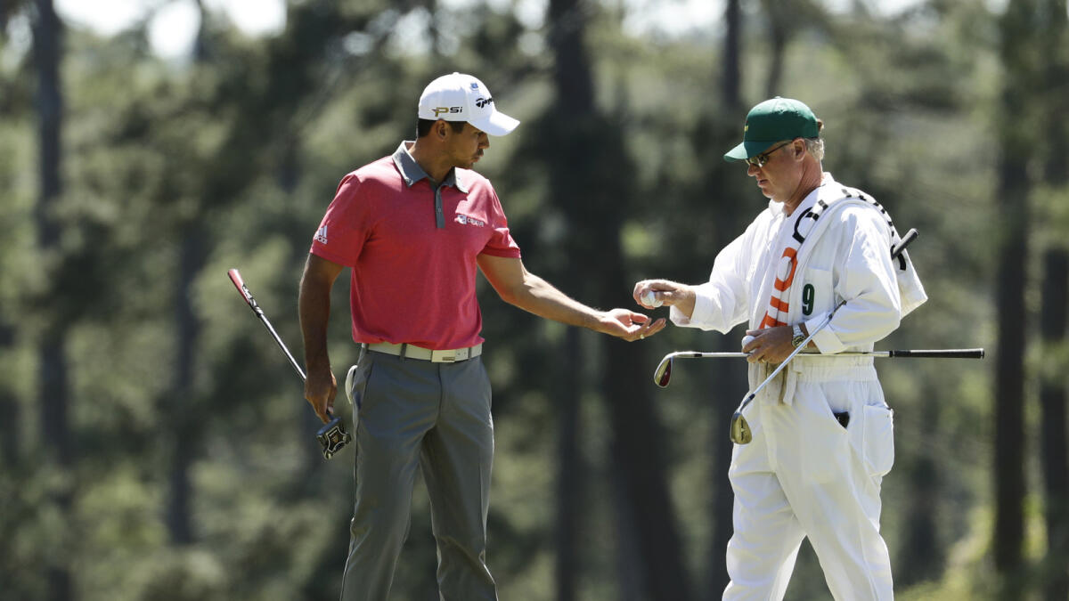 Jason Day gets balls from his caddie Colin Swatton during a practice round for the Masters golf tournament. —