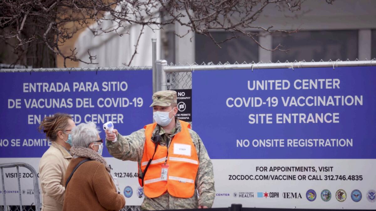 An Illinois National Guardsman takes the temperature of residents arriving at a mass Covid-19 vaccination centre. — AFP