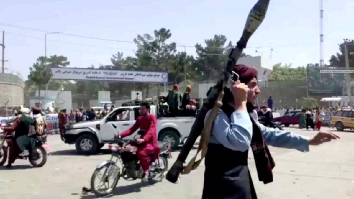 A Taliban fighter runs towards crowd outside Kabul airport. — Reuters