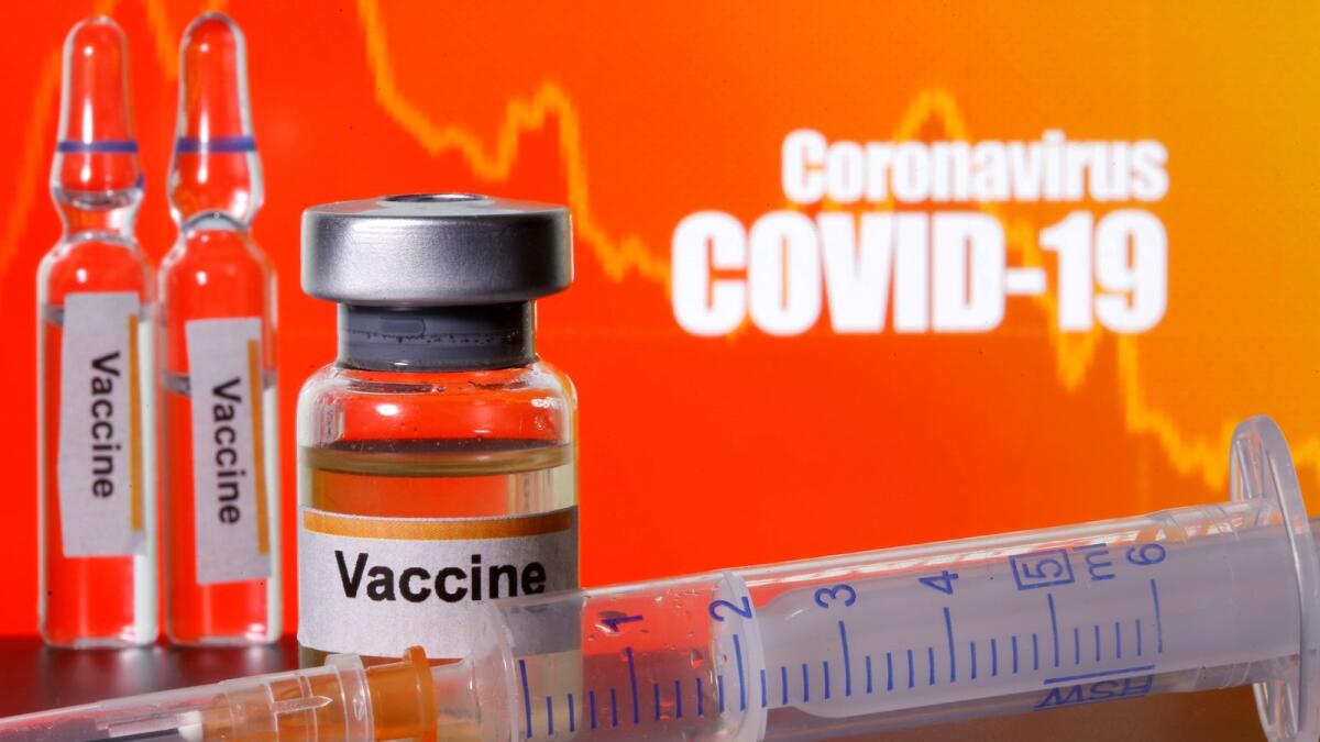 FILE PHOTO: Small bottles labelled with 'Vaccine' stickers stand near a medical syringe in front of displayed 'Coronavirus COVID-19' words in this illustration taken April 10, 2020. REUTERS/Dado Ruvic/Illustration/File Photo/File Photo