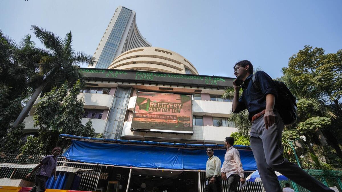 People walk past the Bombay Stock Exchange building in Mumbai on Wednesday. With Budget announcements the 30-share BSE benchmark Sensex rose 1,000 points to touch an intra-day high of 60,1618 points but later pared down to 59,257, after dropping 450 points.  - PTI