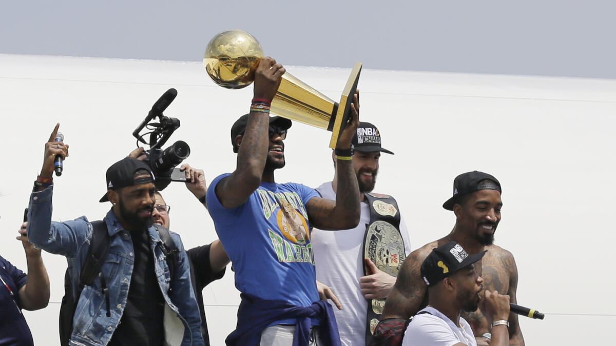 Cavaliers’ LeBron James holds up the NBA Championship trophy alongside teammates after arriving in Cleveland. — AP