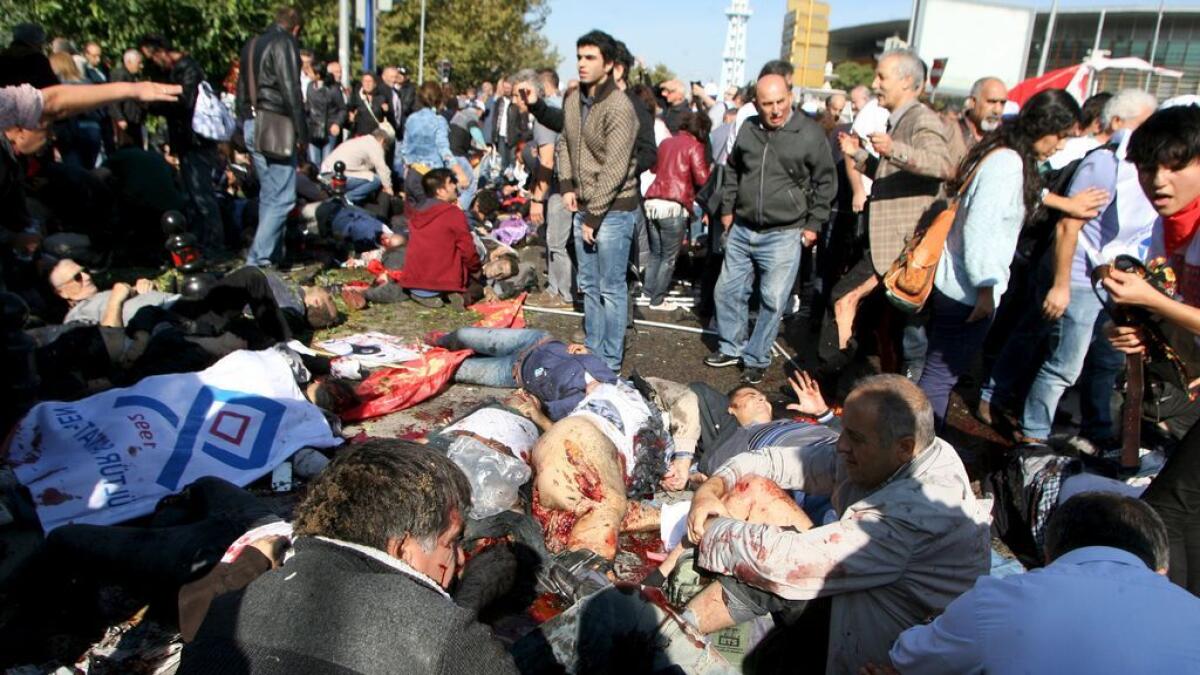People lay on the ground as survivors surround them to offer help after an explosion during a peace march in Ankara, Turkey