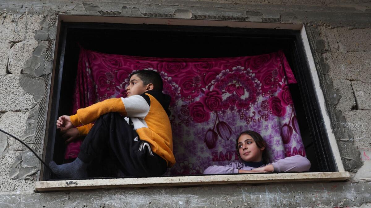Palestinian children look on from a window, in the aftermath of Israeli strikes on houses  in Khan Younis on Wednesday. — Reuters