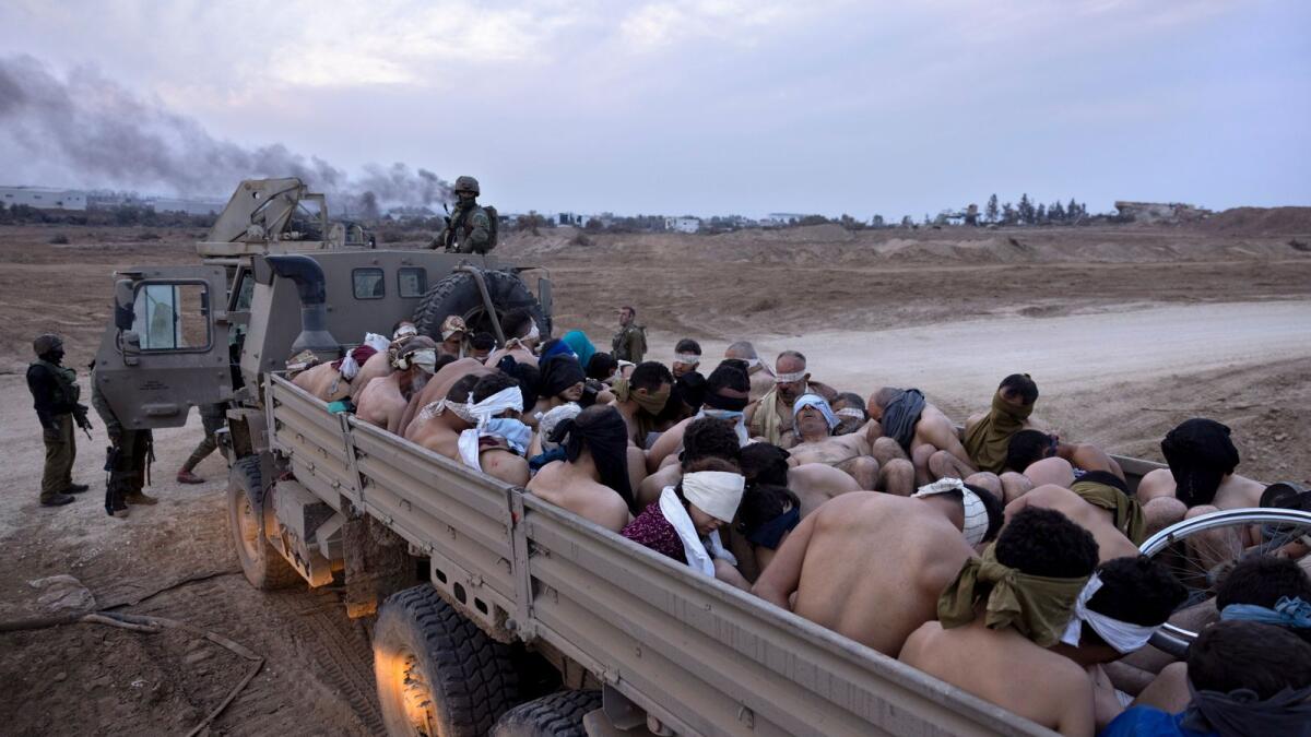 Israeli soldiers stand by a truck packed with bound and blindfolded Palestinian detainees in Gaza. — AP file