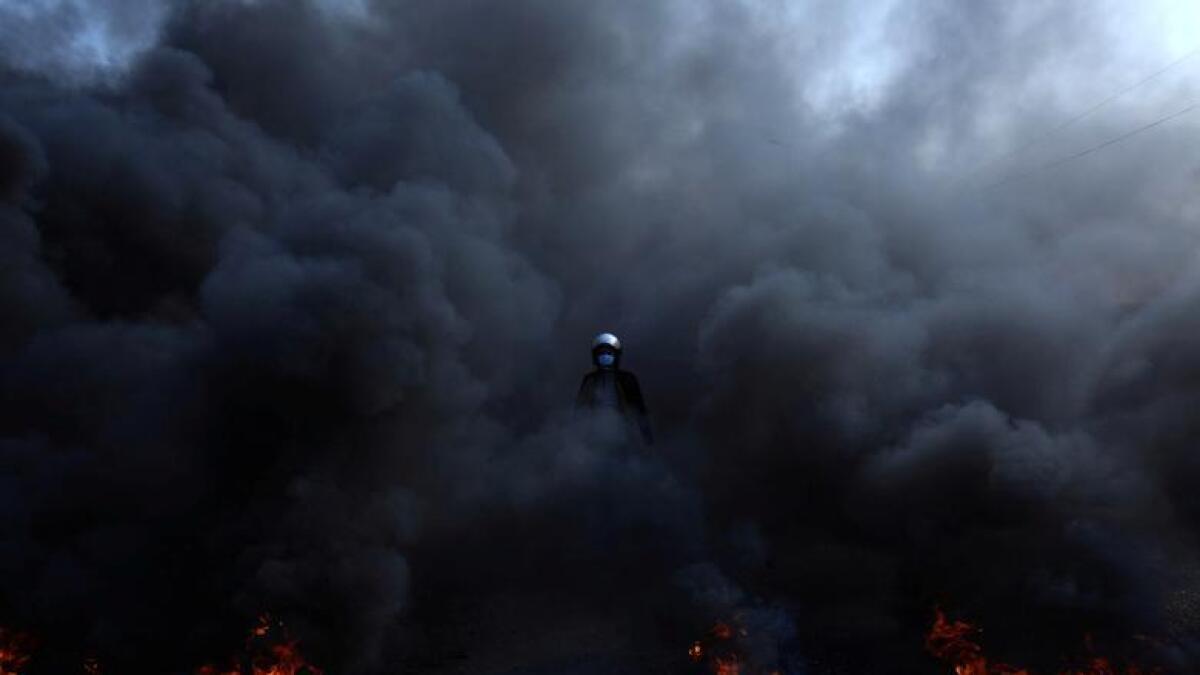 A protester walks amid a cloud of smoke from burning tires during ongoing anti-government protests in Kerbala, Iraq November 26, 2019. - Reuters