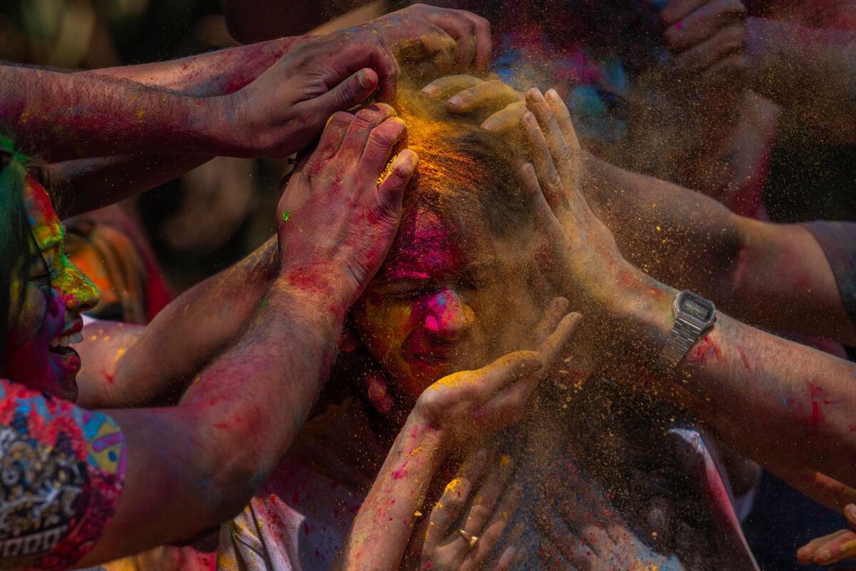 A girl has her face smeared with coloured powder as they celebrate Holi in Mumbai on Monday. — AP