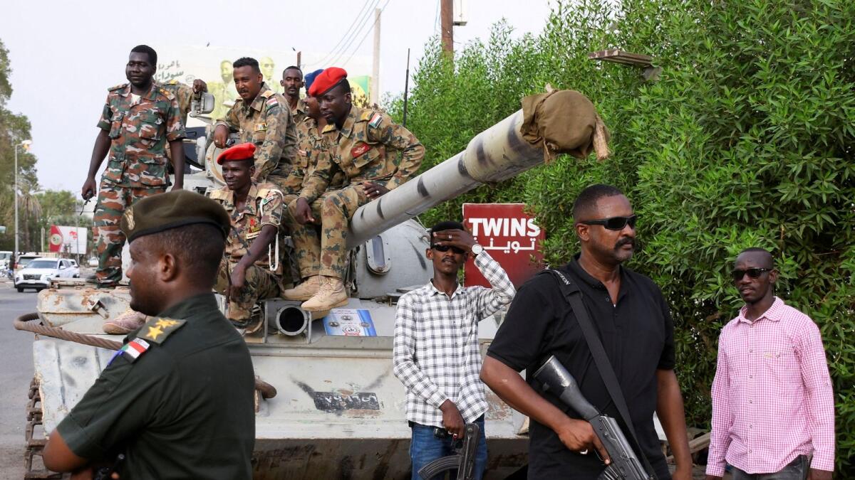 Members of military armed guard and members in plainclothes are seen around a tank in Khartoum. — Reuters