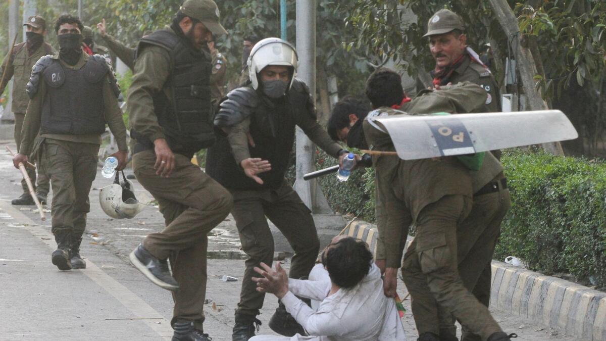 Police officers detain a supporter of former prime minister Imran Khan during clashes in Lahore on Wednesday. — Reuters