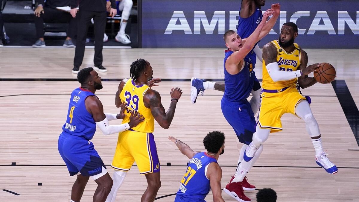 Los Angeles Lakers forward LeBron James (right) attempts to make a pass as Denver Nuggets' Nikola Jokic (second from right) defends