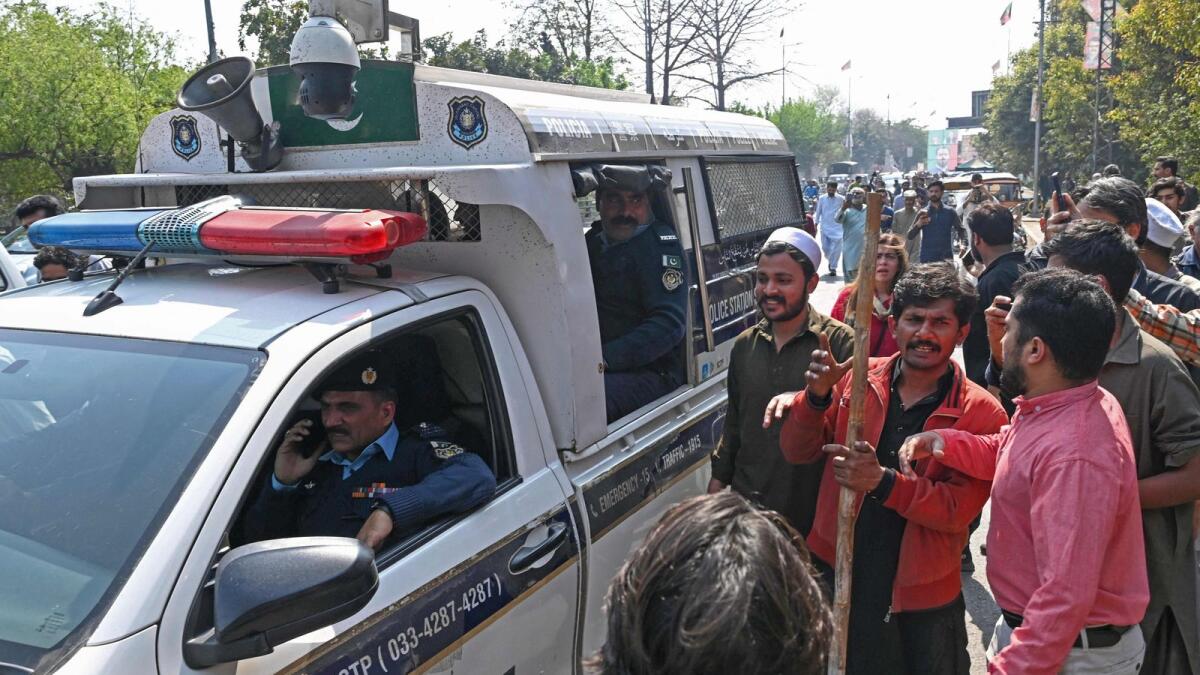 Supporters of former Pakistan prime minister Imran Khan gather around police van outside his house in Lahore. — AFP
