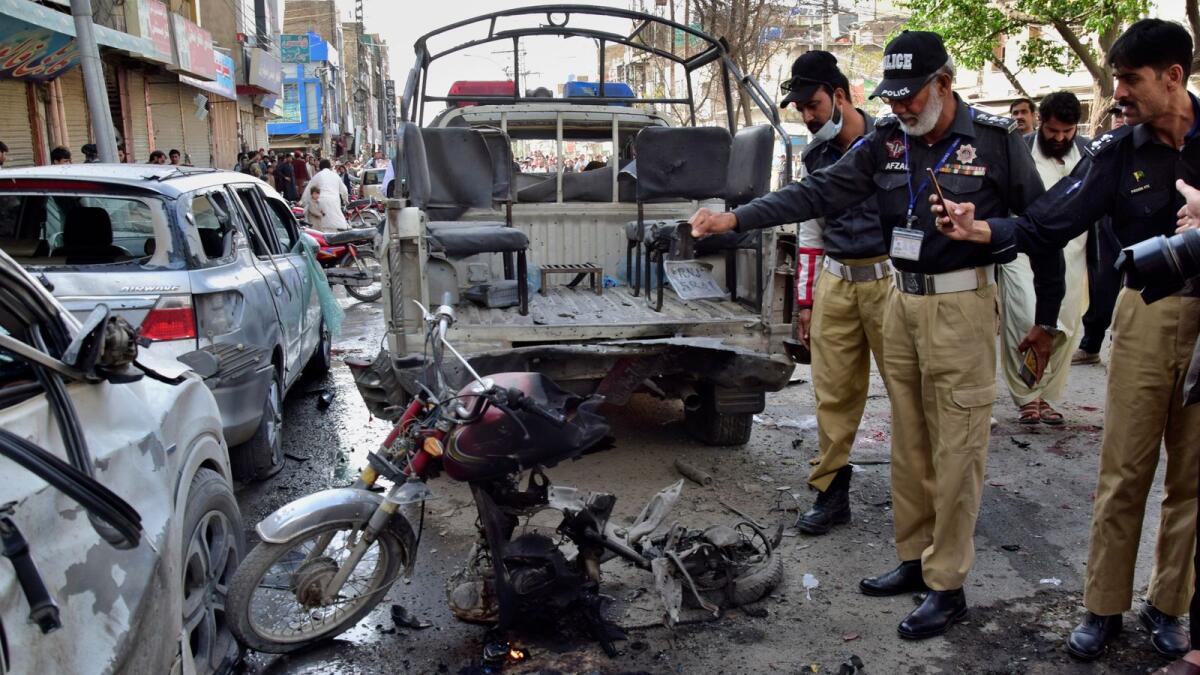 Police officers inspect the site of a bomb blast in Quetta, Pakistan, on Monday. — AP
