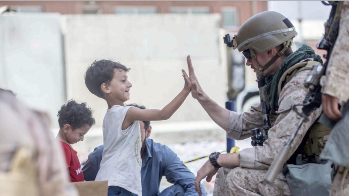 A US Marine gives a high five to a child during an evacuation at Hamid Karzai International Airport in Kabul. — AP