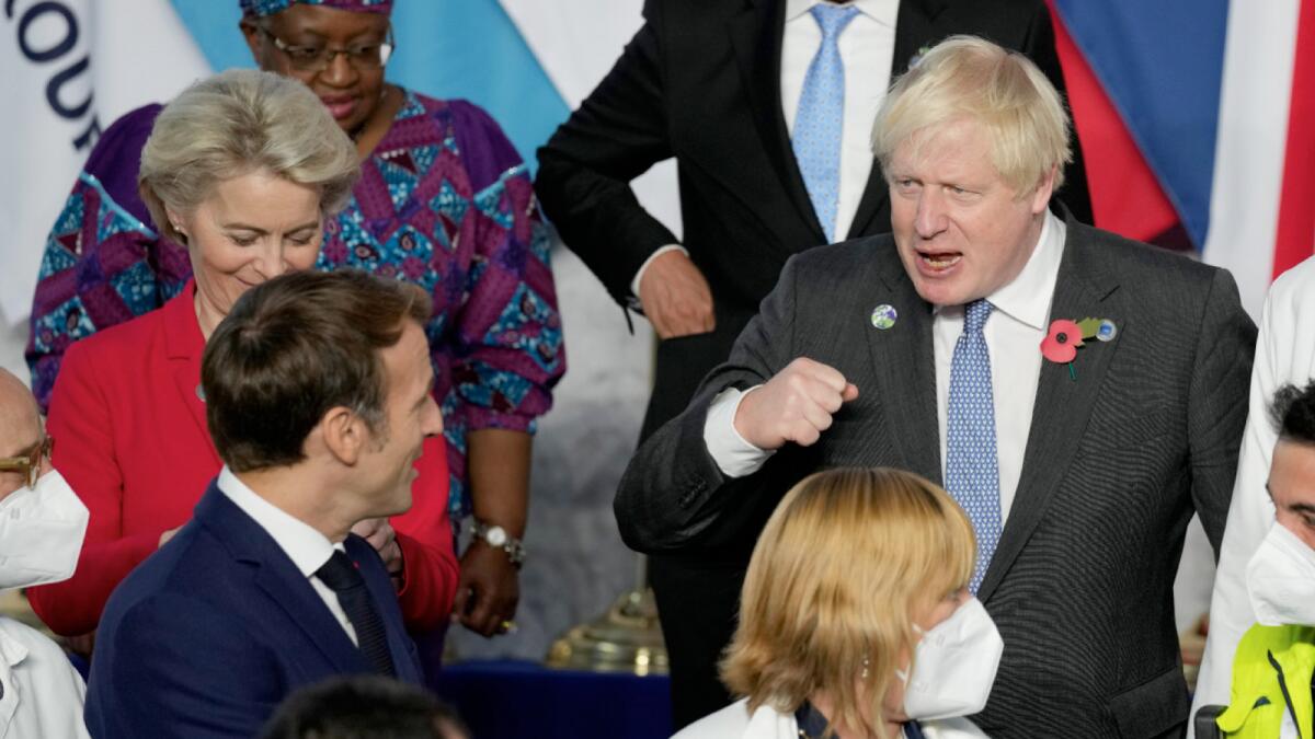 British Prime Minister Boris Johnson pumps fists with French President Emmanuel Macron during a group photo at the G20 summit in Rome. – AP