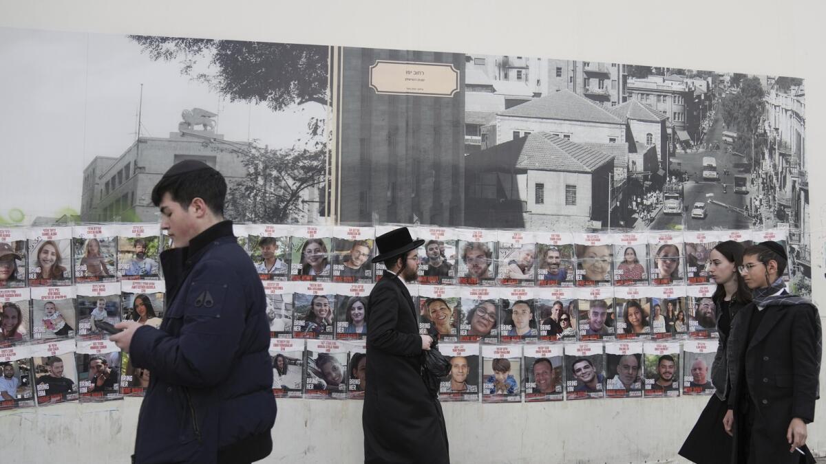 People pass by a wall with photos of about 240 hostages who were abducted during the October 7, Hamas attack on Israel. in Jerusalem. - AP