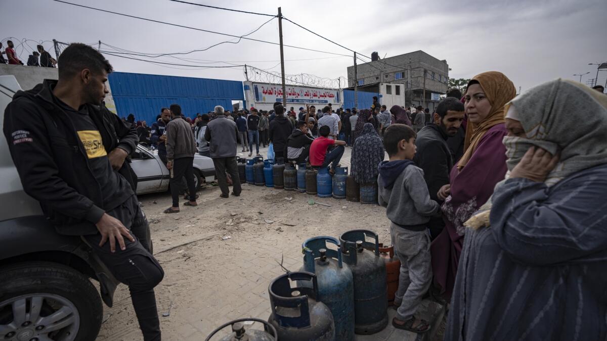 Palestinians line up for cooking gas during the second day of the temporary ceasefire between Hamas and Israel in Khan Younis. — AP