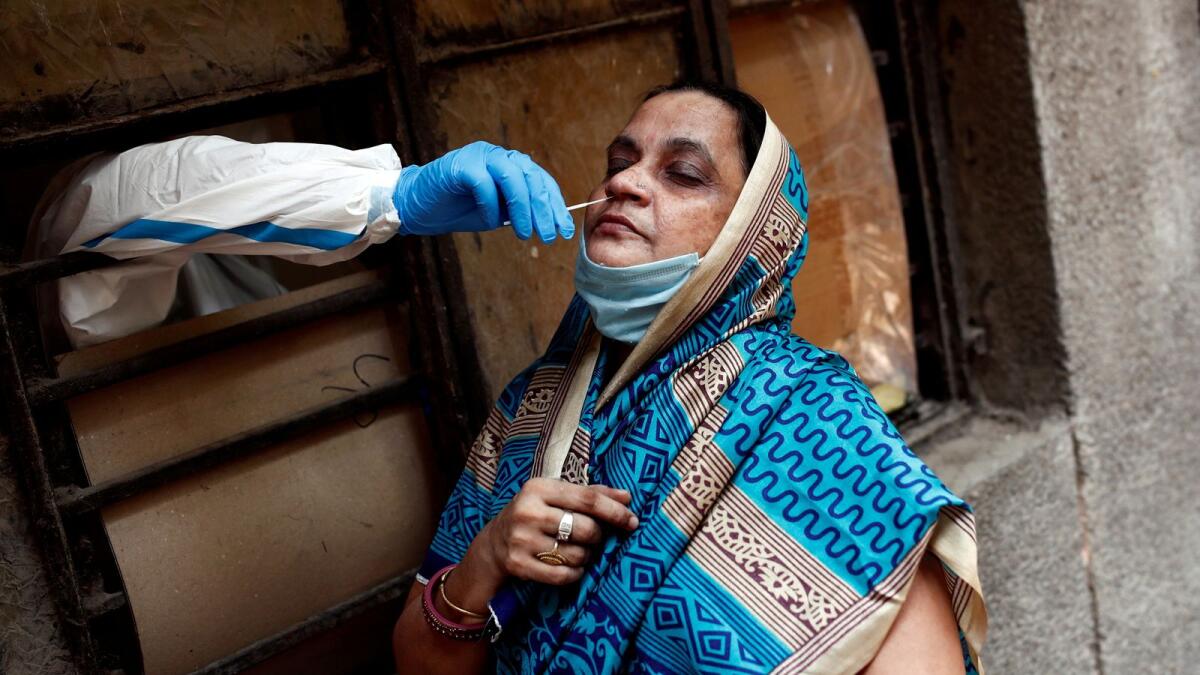 A medical worker collects a sample from a woman at a school in New Delhi. — Reuters
