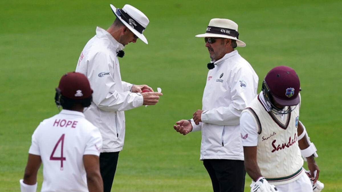Umpire Michael Gough (left) disinfects the ball after Dom Sibley (unseen) accidentally used saliva to polish it during the fourth day of the second Test at Old Trafford. - Twitter