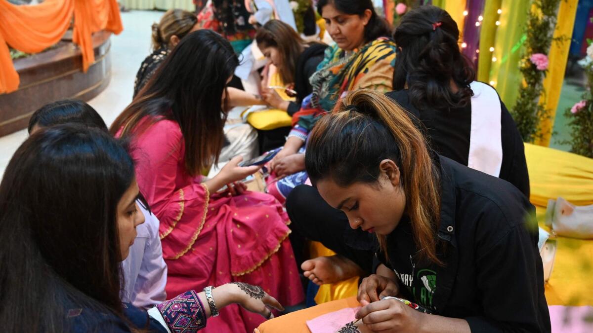 CORRECTION / Beauticians applie 'henna' design on customers' hand at at a mall ahead of Eid al-Fitr festival, which marks the end of the holy fasting month of Ramadan, in Islamabad on April 21, 2023.  (Photo by Aamir QURESHI / AFP)
