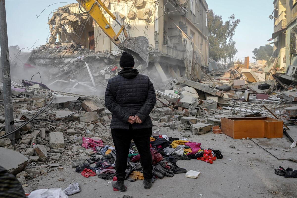 A local resident, whose loved ones are still under the rubble, stand in front of the collapsed buildings in Hatay on February 15, 2023. Photo: AFP