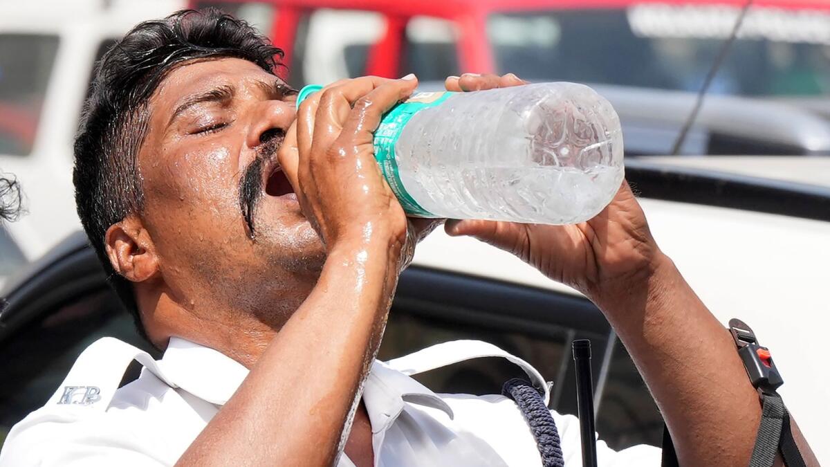 A traffic police constable quenches his thirst during a hot summer day in Kolkata. — PTI