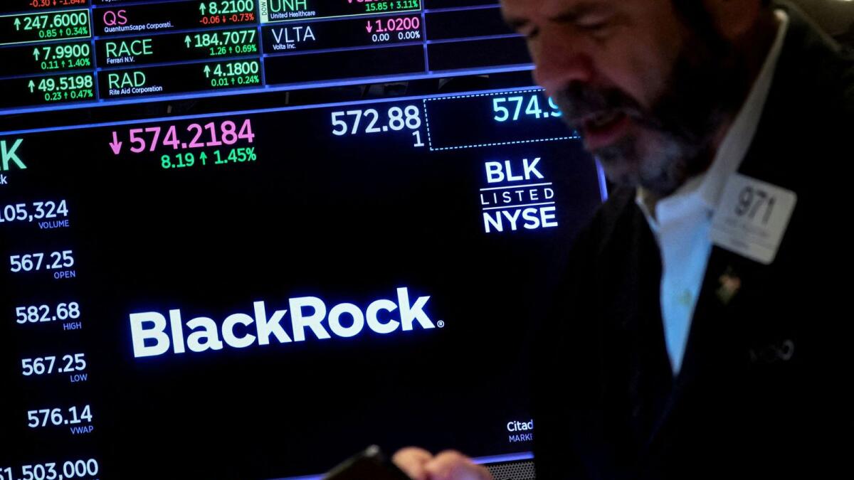A trader works as a screen displays the trading information for BlackRock on the floor of the New York Stock Exchange. — Reuters