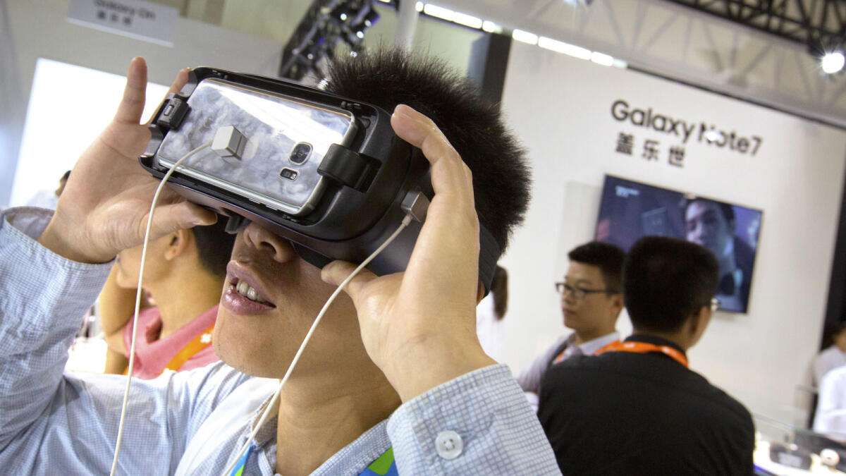 A visitor tries out a Samsung Gear VR headset at a Samsung Electronics display booth during an electronics expo in Beijing, Wednesday, Sept. 21, 2016. AP