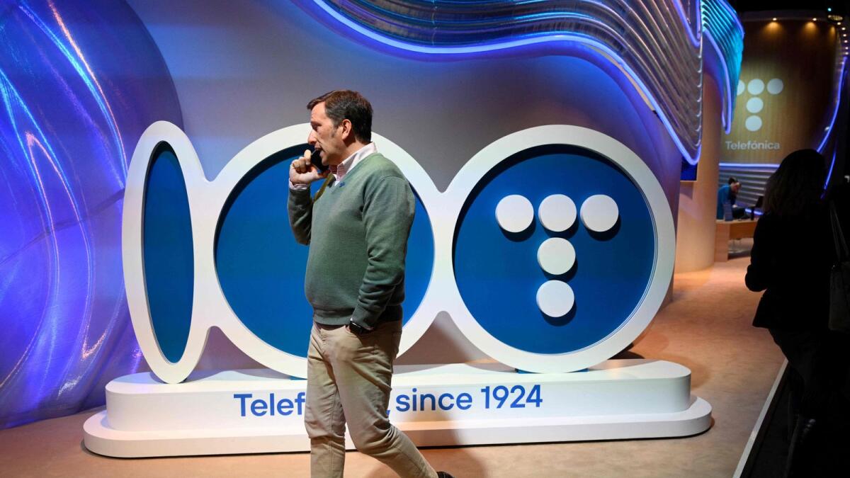 A visitor talking on the phone walks past a Telefonica logo during the Mobile World Congress (MWC) in Barcelona. — AFP file