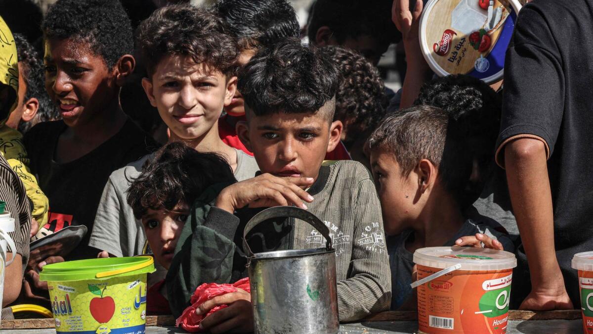 Palestinian children queue to receive a portion of food at a make-shift charity kitchen in Rafah in the southern Gaza Strip on November 8. — AFP