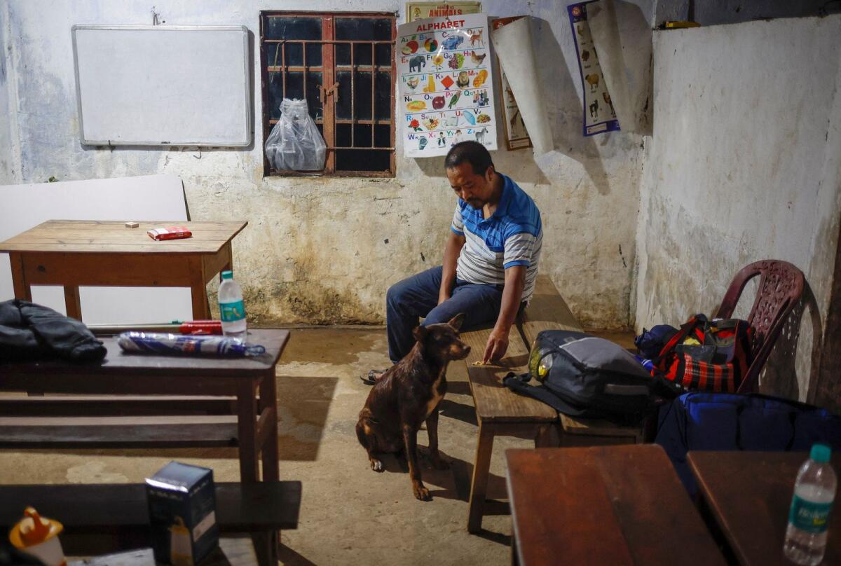Polling officer W. Moning Belgit Monsang feeds a dog inside a polling booth after reaching Nongriat village, a remote polling station. — Reuters