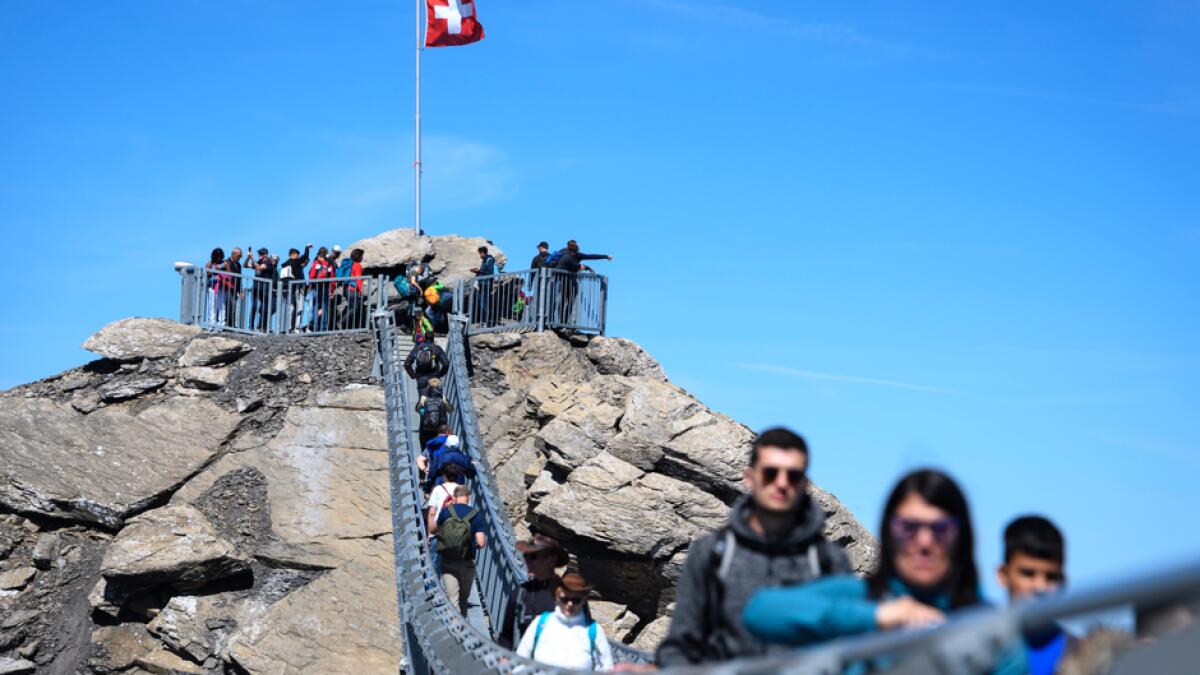 Tourists walk on the 'Peak Walk' suspension bridge of Glacier 3000 during the coronavirus disease outbreak, in Les Diablerets, Switzerland. In Switzerland, from July 6, people aged 12 and over must wear a mask in all public transport, trains, trams and buses, as well as in cable cars and boats. Photo: AP