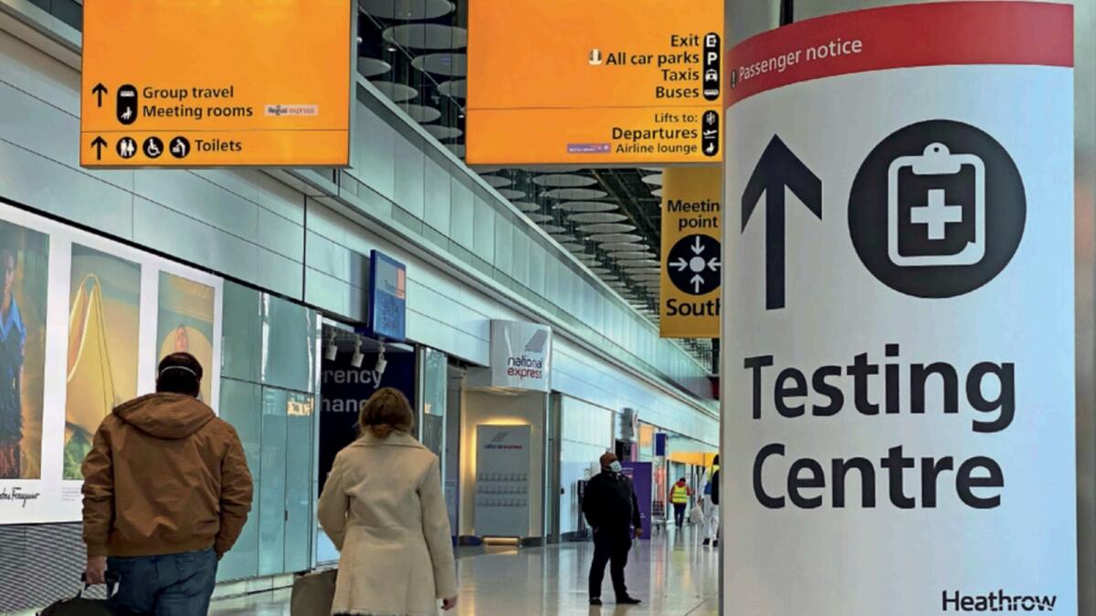 Travellers pass a sign for a Covid-19 test centre at Heathrow Airport in February. — Reuters file