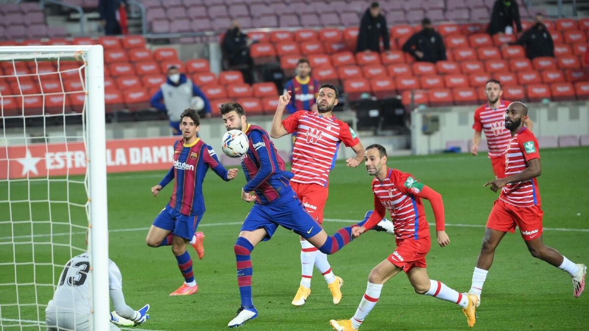 Barcelona defender Gerard Pique (centre) jumps for the ball during the La Liga match against Granada at the Camp Nou on Thursday. (AFP)