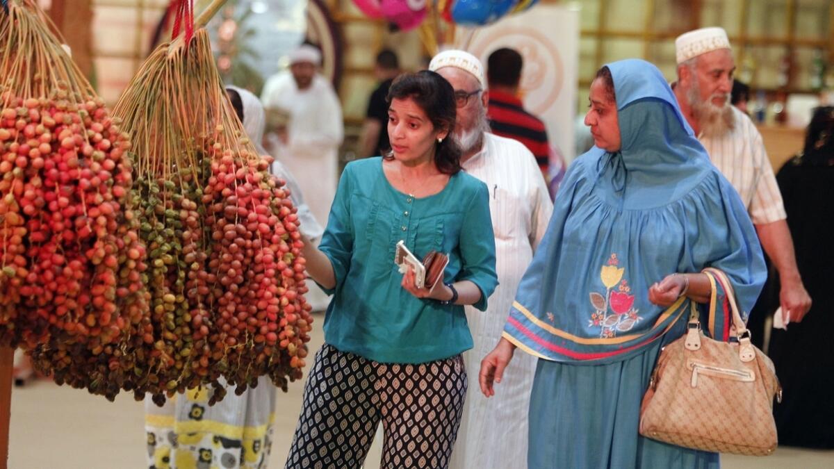 A TREAT FOR THE EYES, TOO ... Visitors check the colourful date bunches at the festival. (M. Sajjad)