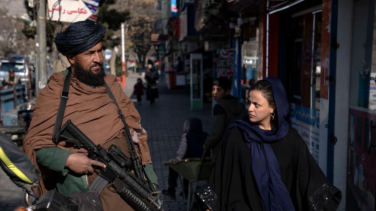 A Taliban fighter stands guard as a woman walks past in Kabul, Afghanistan, on Dec. 26, 2022. — AP file