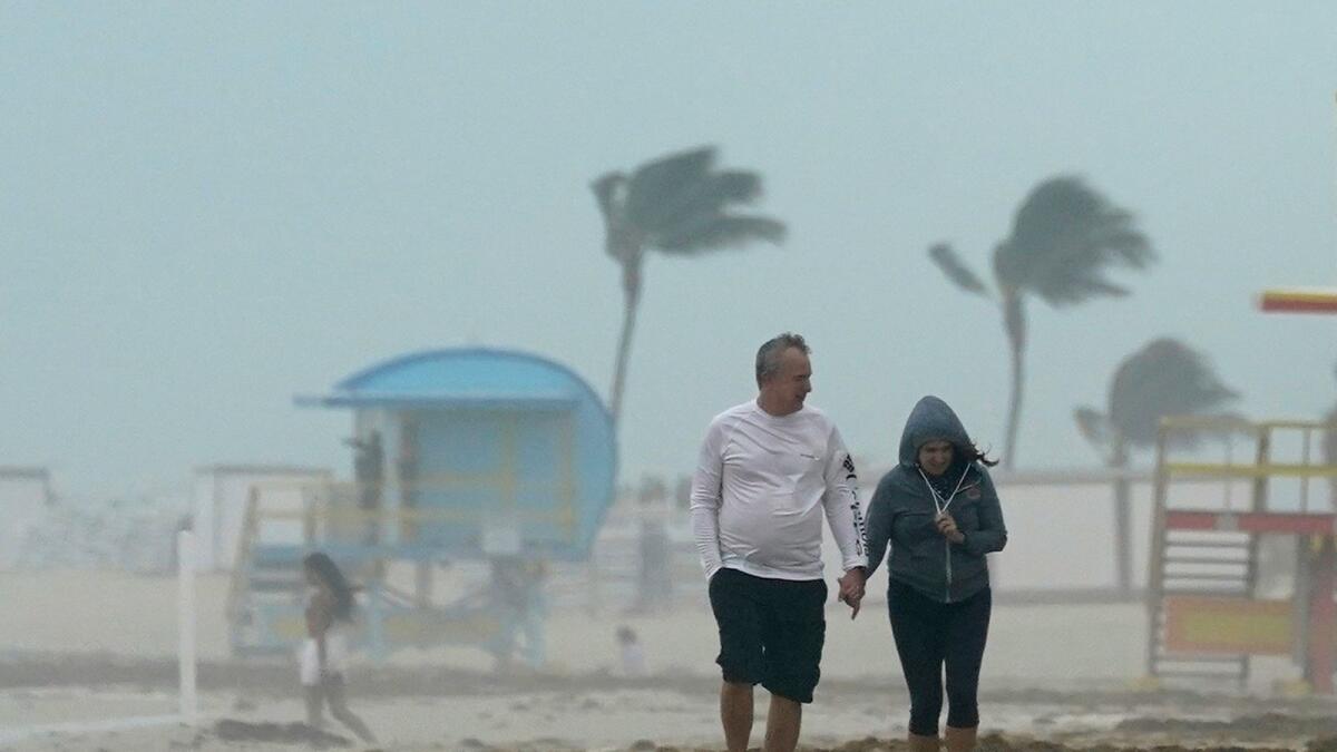 A couple walks along the beach during a downpour on November 8, 2020, on Miami Beach, Florida’s famed South Beach.