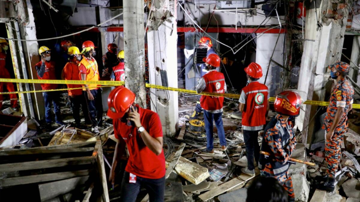 Rescue workers at the site after a blast in a shop in Dhaka. — Reuters