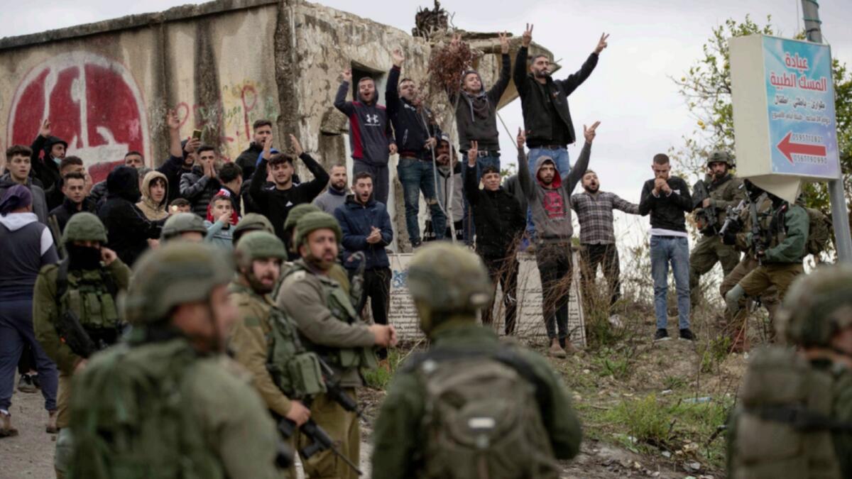 Israeli soldiers stand between Palestinians and a Jewish settler following a settler attack on the West Bank village of Burqa after an Israeli settler was shot dead by Palestinian gunmen. — AP
