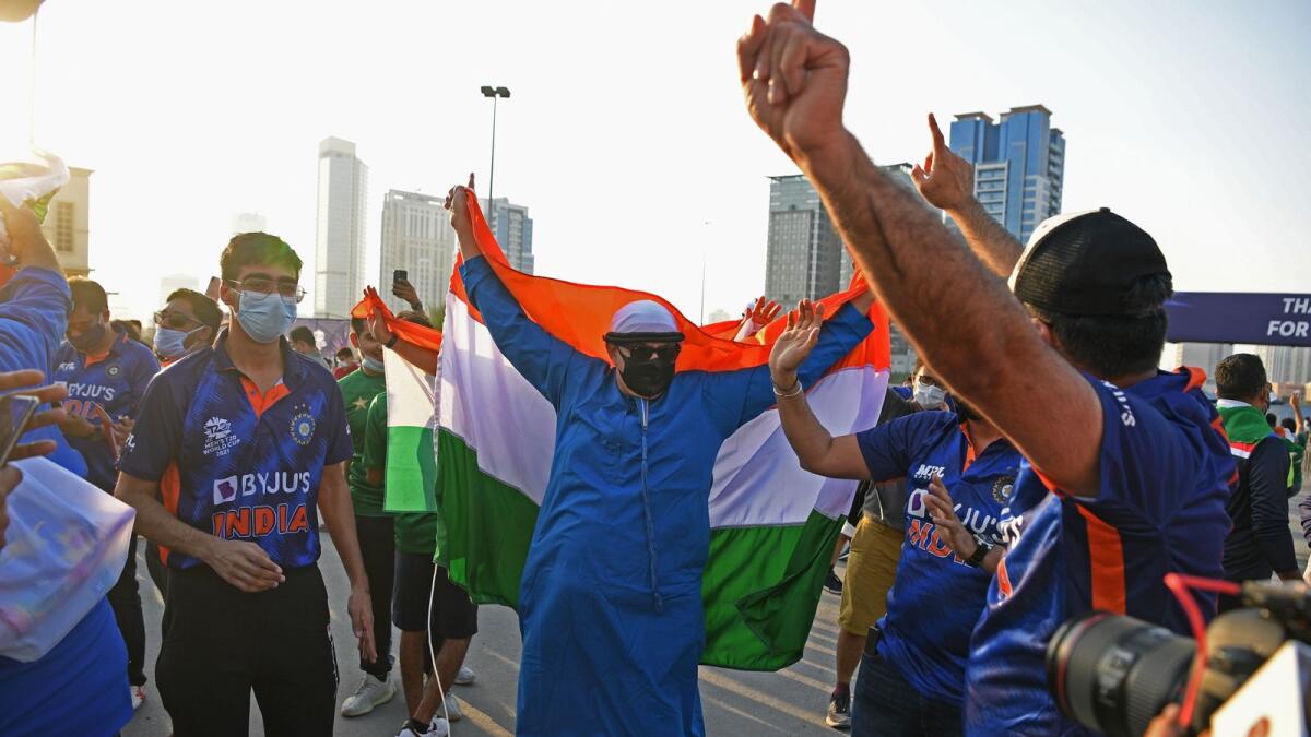 Fans of Indian cricket team cheer while holding country's national flag outside the Dubai International Cricket Stadium. (Photo: AFP)