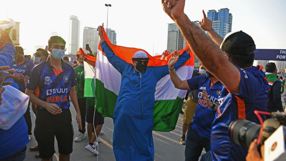 Fans of Indian cricket team cheer while holding country's national flag outside the Dubai International Cricket Stadium. (Photo: AFP)