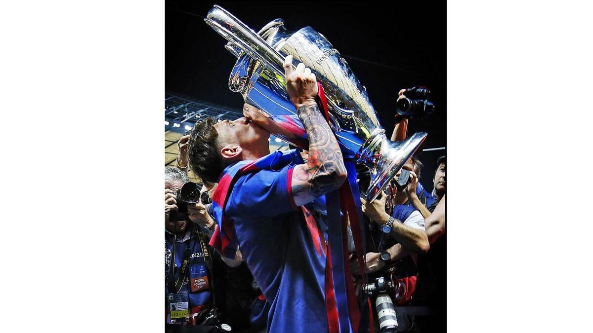 Messi kisses the Champions League trophy after winning it for the fourth time as photographers try to catch the perfect snap.