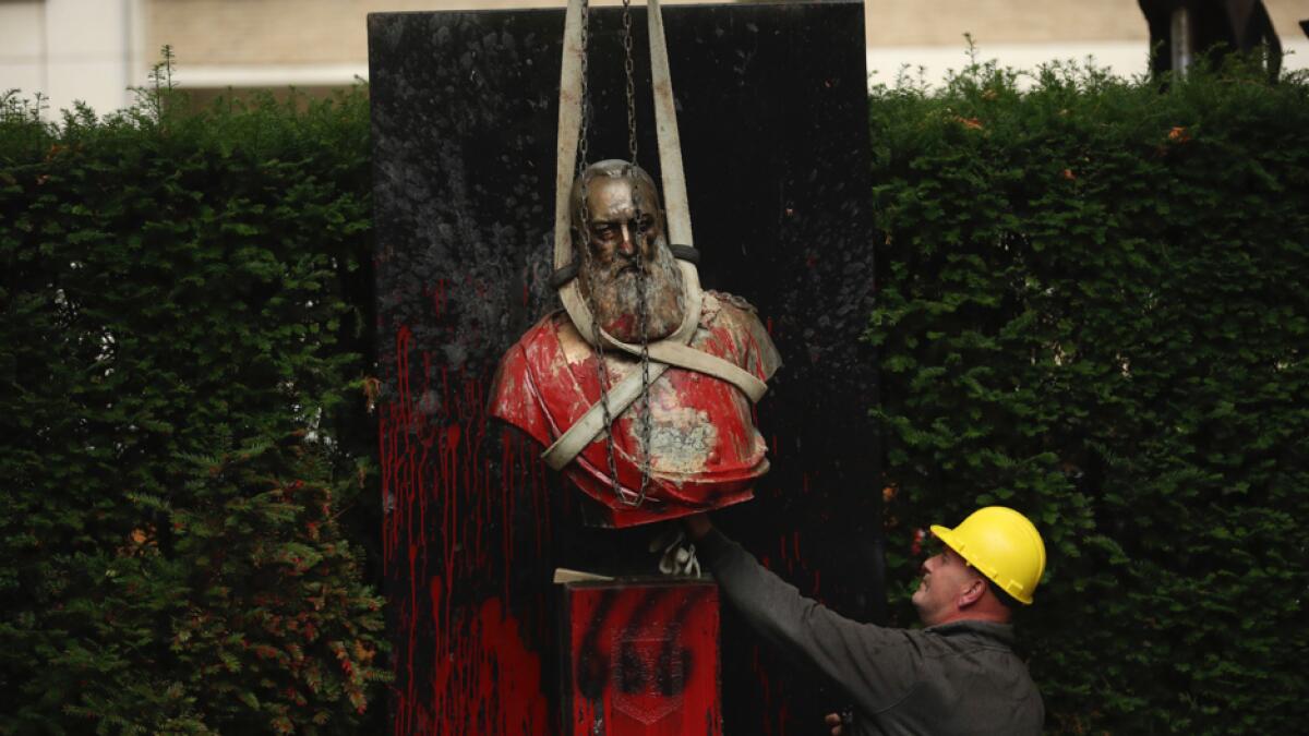 A bust of Belgium's King Leopold II is hoisted off of its plinth by a crane as it's removed from a park in Ghent, Belgium. Photo: AP