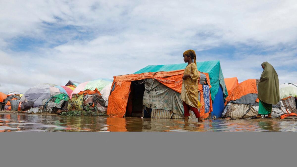 Residents wade through flood waters within their makeshift shelters at the Al Hidaya camp for the internally displaced people following heavy rains in the outskirts of Mogadishu, Somalia. — Reuters