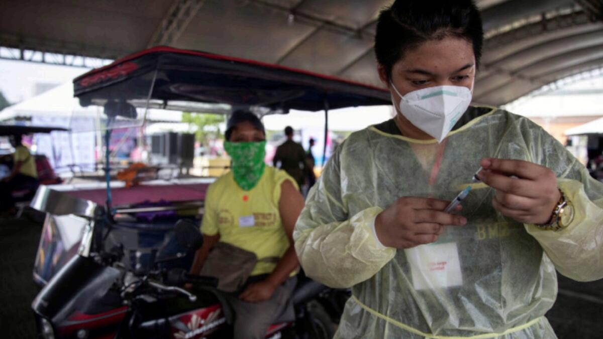 A health worker prepares to vaccinate a public transport driver with Covid-19 vaccine in a shopping mall's parking lot turned into a drive-thru vaccination site, in Quezon City, Metro Manila. — Reuters