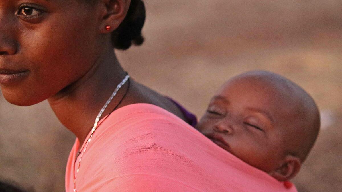 A woman carries her baby on her back as Ethiopian refugees who fled fighting in Tigray province take refuge at the Um Rakuba camp in Sudan’s eastern Gedaref province.