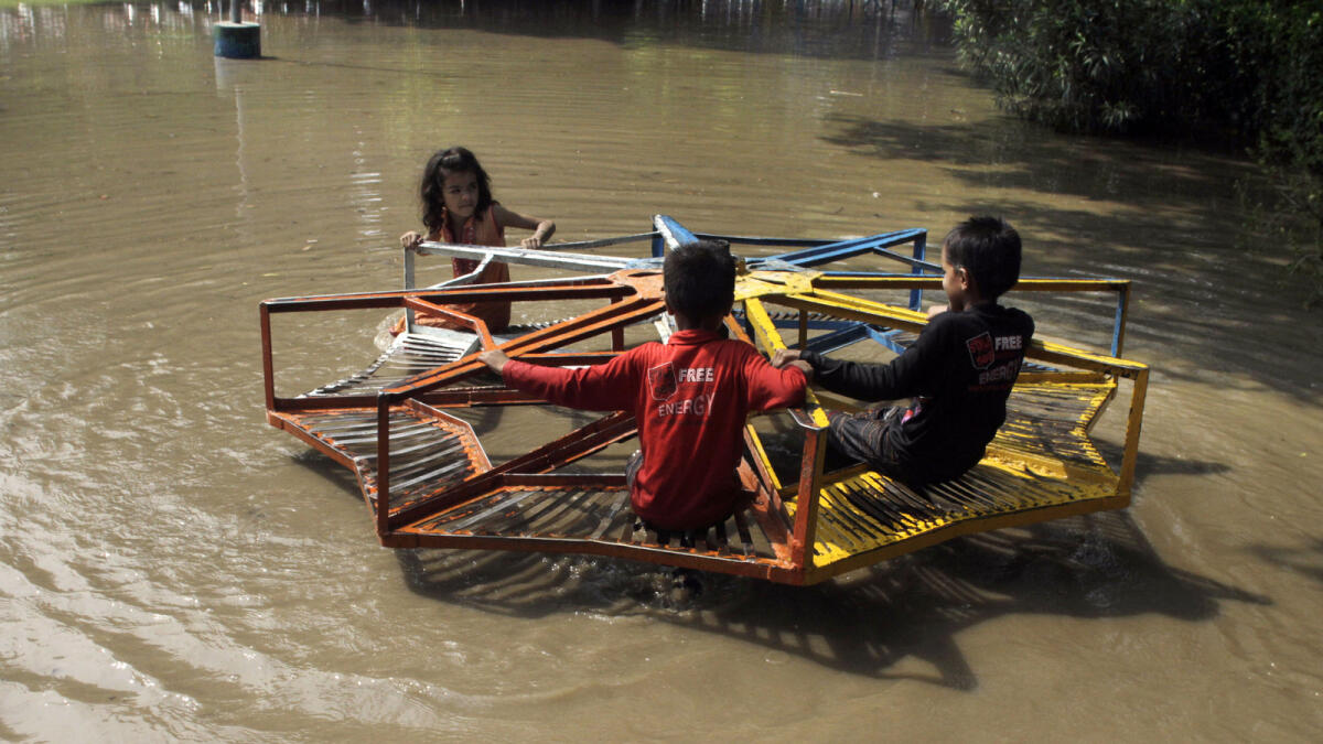 Pakistani children take a ride on a roundabout at a flooded park caused by heavy rains in Lahore, Pakistan