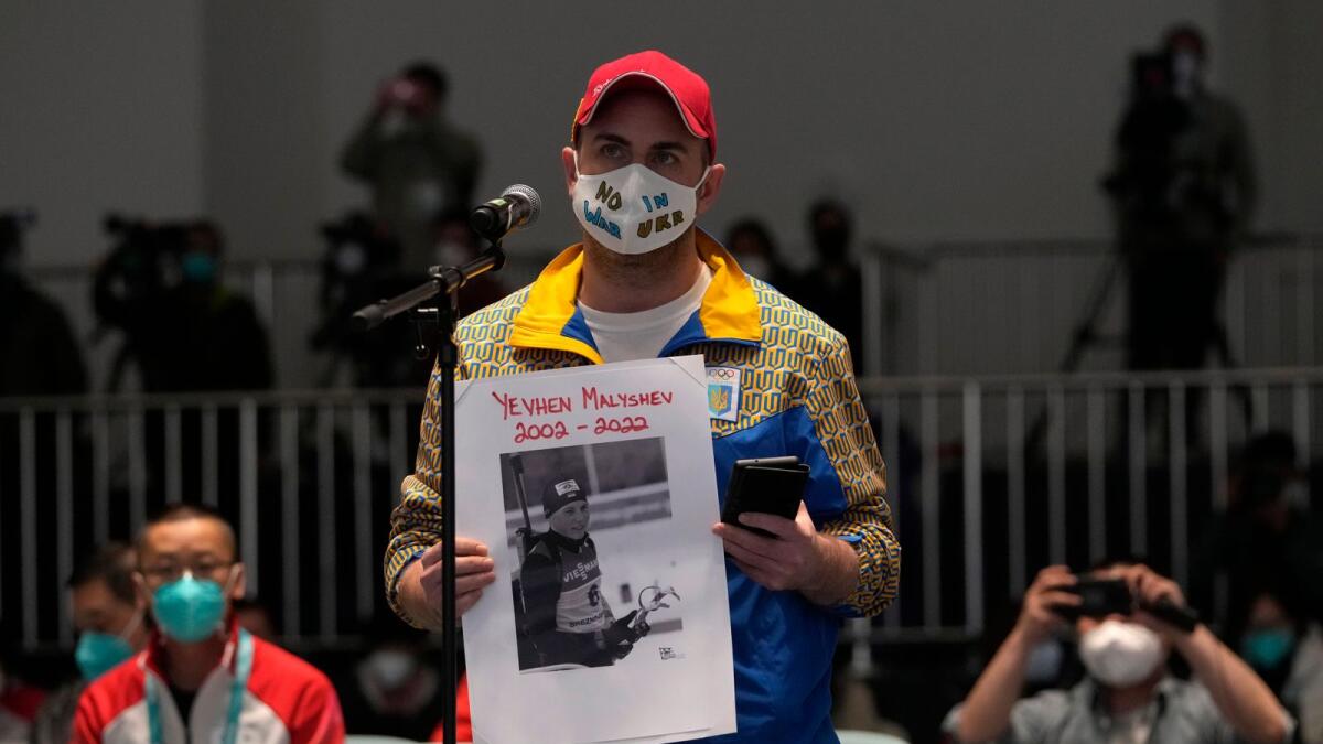 A journalist from Ukraine holds a photo of Yevhen Malyshev, an athlete who represented Ukraine’s junior biathlon team, during a Winter Paralympic Games press conference in Beijing on Wednesday. According to the International Biathlon Union, Malyshev died serving the Ukrainian military in the conflict with Russia. (AP)
