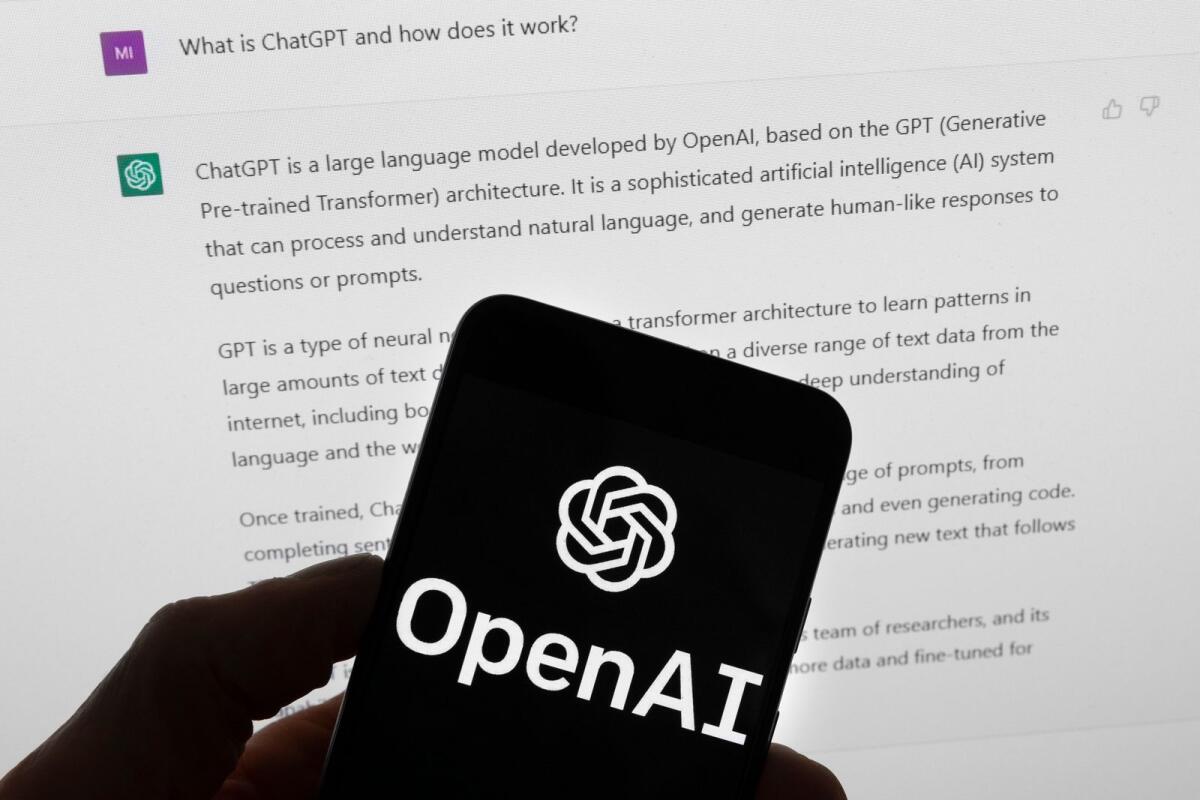 The OpenAI logo is seen on a mobile phone in front of a computer screen which displays output from ChatGPT, Tuesday, March 21, 2023, in Boston. – AP